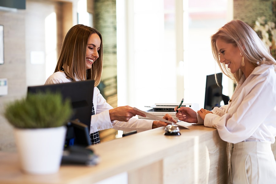 Wiggins Shredding provides shredding services for hotels like this one with a businesswoman at hotel front desk